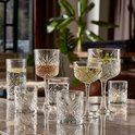 Diverse kristallen glazen op marmeren tafel, waaronder wijnglazen gevuld met witte wijn en waterglazen met munt.