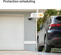 Beveiligingscamera aan de muur bij een witte garagedeur, met een auto ernaast. Tijd schema 08:00-18:00 aan.