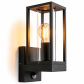 Moderne zwarte wandlamp met glazen cilinder en zichtbare E27 lamp, inclusief bewegingssensor.