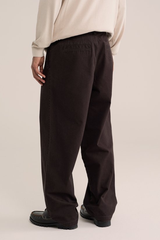 Achterkant van een man in beige coltrui en bruine chino.