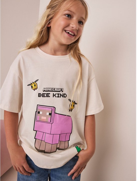 Crème oversized T-shirt met Minecraft print van een roze schaap en bijen. Tekst 'MINECRAFT BEE KIND'.