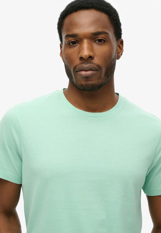Gros plan d'un homme portant un t-shirt Superdry vert menthe.