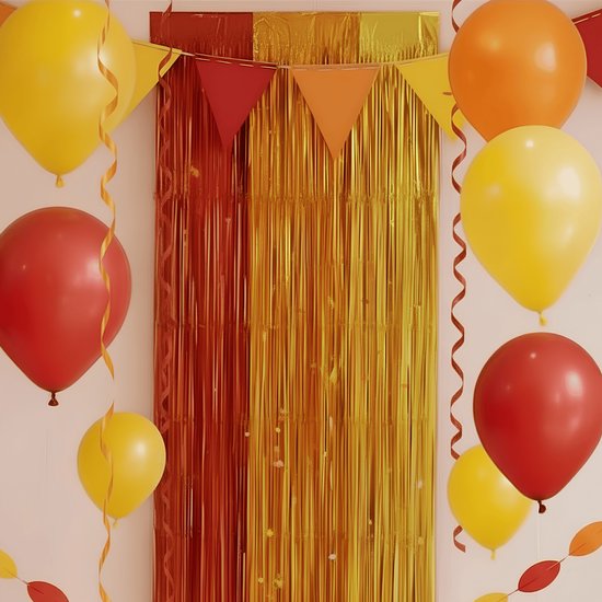 Feestelijke decoratie met rode, oranje en gele ballonnen en slingers voor een glittergordijn.