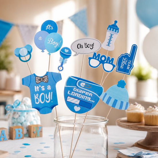 Kinderfeest decoraties met blauwe en witte baby items zoals een romper met 'It's a Boy!' en een luier met 'Diaper Loading...' tekst.