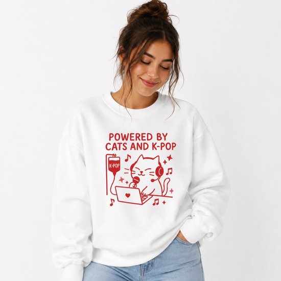 Femme aux cheveux bruns en chignon porte un sweat blanc avec imprimé rouge d'un chat avec casque, microphone et ordinateur portable.