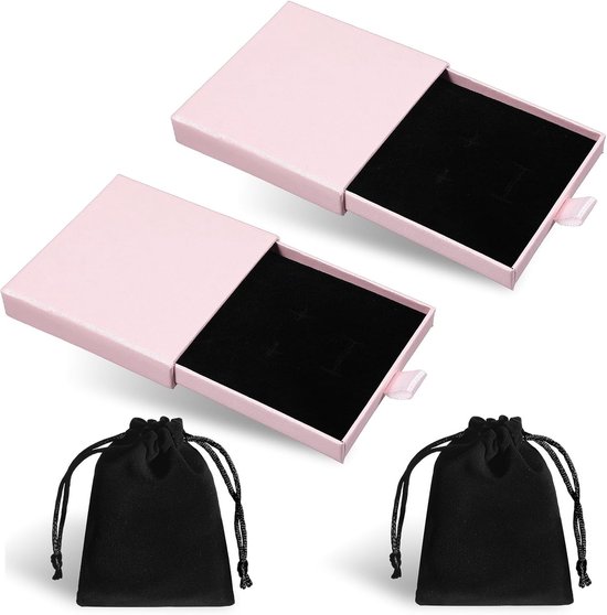 Twee open roze geschenkdozen met zwarte fluwelen voering, naast twee zwarte fluwelen zakjes met trekkoord.