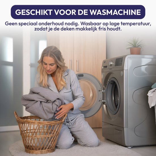 Een vrouw in pyjama doet een grijs dekbed in de wasmachine.