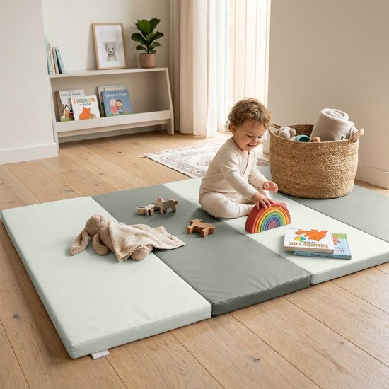 Baby speelt op een beige en grijze speelmat in een kinderkamer.