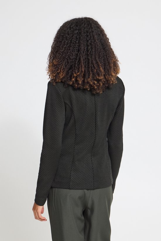 Aanzicht op de rug van een model met krullend haar, draagt een zwarte blazer met diagonaal patroon.