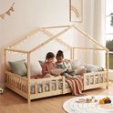 Deux enfants lisant un livre dans un lit maison en bois naturel avec barreaux et guirlande.