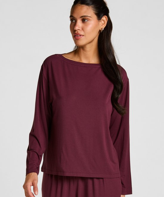 Een bordeauxrode top met lange mouwen, gedragen door een model dat naar de zijkant kijkt.