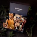 Een open borrelbox vol met kazen, worst, crackers, chips, noten, saus en dennentakken.