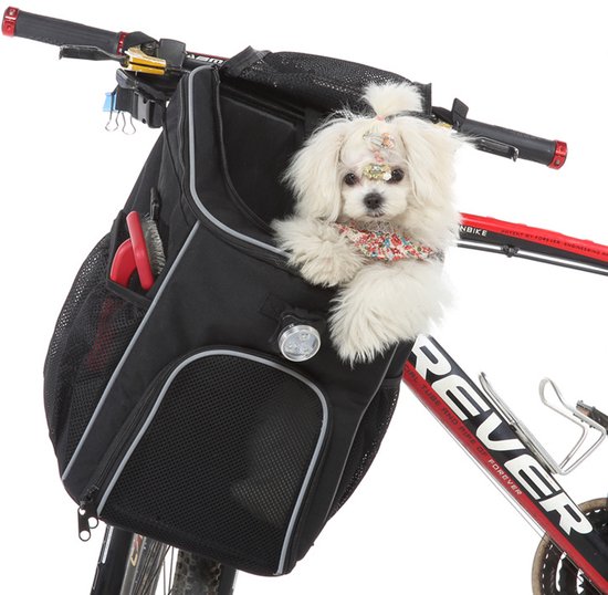 Zwarte fietsmand met een witte hond, bloemenbandje en haarclips, gemonteerd op een fiets.