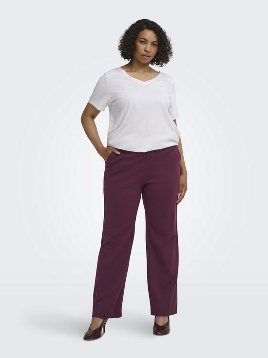 Model met lange bordeauxrode broek met rechte pijpen, witte top en hakken.
