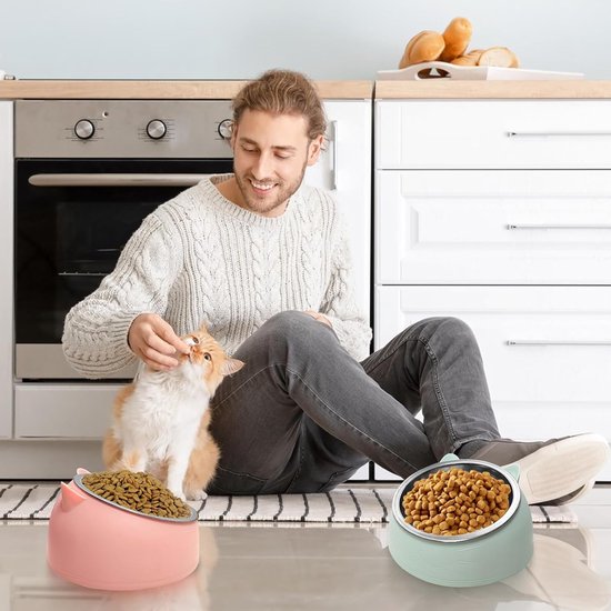 Man die kat eten geeft, naast roze en groene kattenvoerbakken met roestvrijstalen kommen.