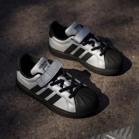 Zilveren Adidas sneakers met zwarte strepen en klittenbandsluiting. Zwarte neuzen en zolen.