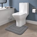 Een grijze badmat met een vierkant patroon ligt voor een witte toiletpot.