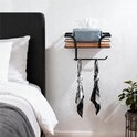 Zwarte wandrek met houten plank en rolhouder. Met tissuebox en twee sjaals.
