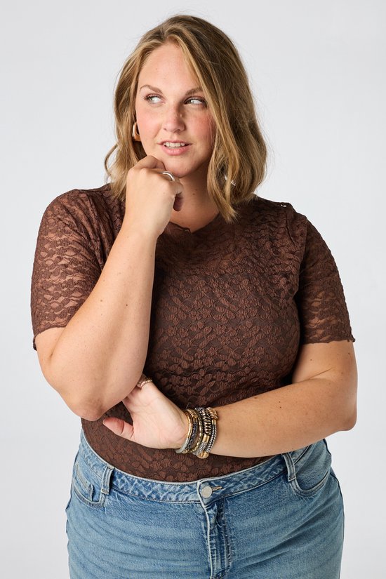 Vrouw met hand op kin, denkend, in bruine kanten top.