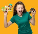Fille aux cheveux bouclés en t-shirt vert tenant une animalerie rose et une jeep, toutes deux en LEGO.