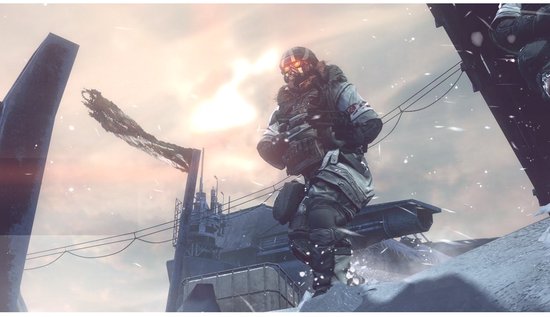 Un soldat de Killzone 3 en tenue d'hiver est accroupi, arme à la main, dans un environnement industriel enneigé.