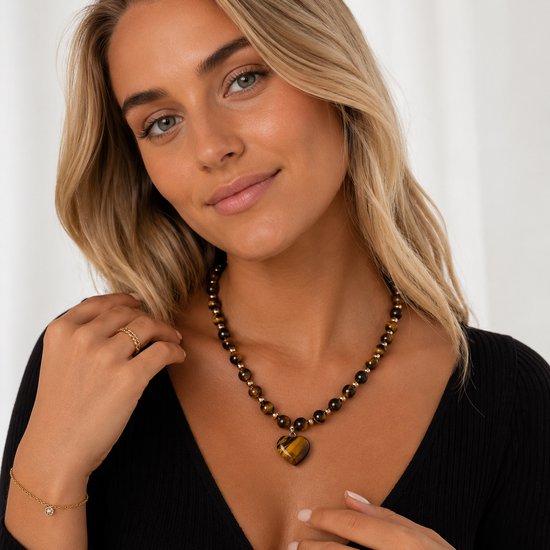 Model met een bruine tijgeroog ketting met gouden kralen en een hartvormige tijgeroog hanger.