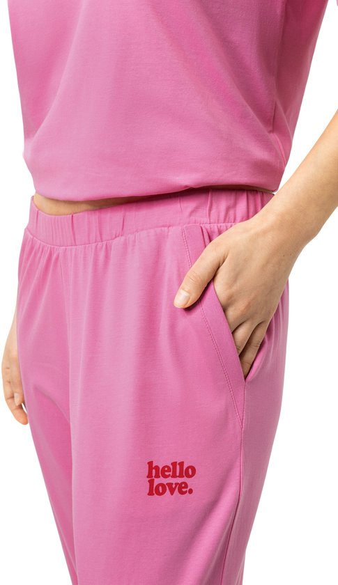 Detailopname van roze pyjamabroek met steekzak en rode tekst 'hello love.'.