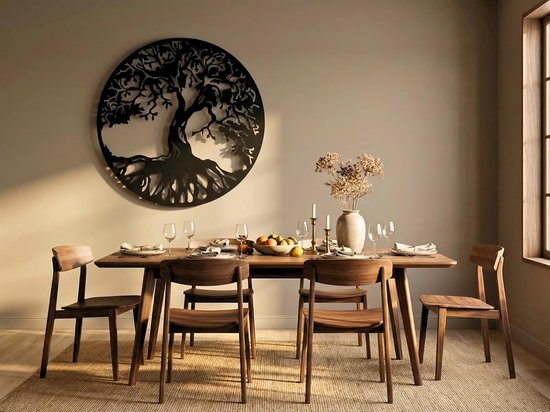 Zwart metalen wanddecoratie in de vorm van een levensboom met dikke takken en wortels, boven een houten eettafel met gedekte tafel.
