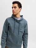 Portret van een man in een blauwgrijze hoodie met subtiel 'JACK & JONES' logo op de borst.