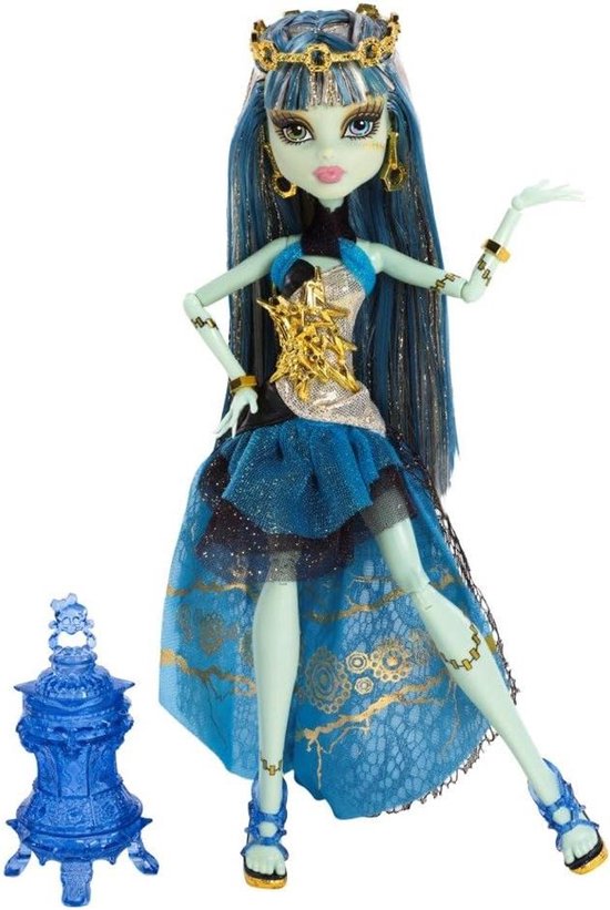 Monster High pop met lang blauw haar, gouden kroon en blauwe jurk met gouden versieringen. Naast de pop staat een blauw accessoire.