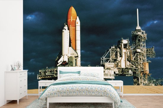 Papier peint de la navette spatiale sur son pas de tir au crépuscule, nez orange et fuselage blanc, dans une chambre.
