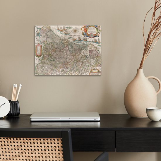 Carte historique des Pays-Bas accrochée à un mur au-dessus d'un bureau avec un ordinateur portable.