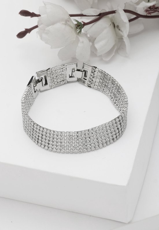 Zilverkleurige armband met vier rijen strass steentjes en een schakelsluiting. Gedecoreerd met witte bloesems.
