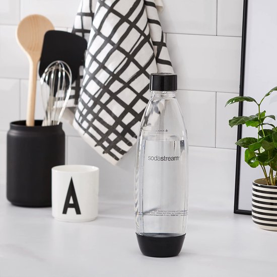 Sodastream fles van helder plastic met zwarte dop en onderkant, op een aanrecht.