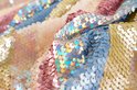 Gedetailleerde close-up van lagen pailletten in goud, blauw en roze.