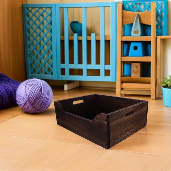 Donkerhouten krat op een houten vloer, naast een paarse bol wol en blauwe decoratie.