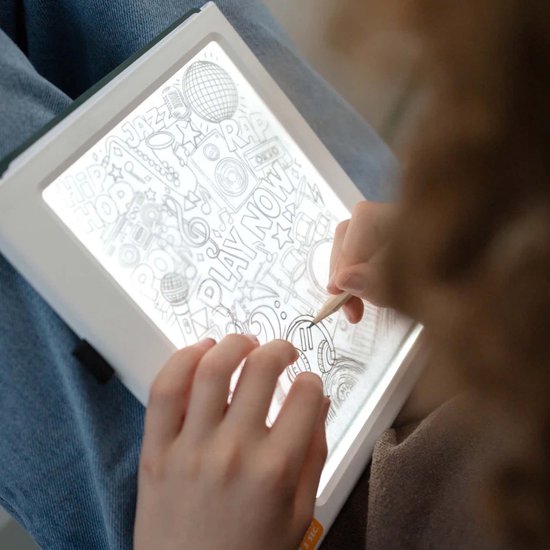 Een meisje kleurt een tekenplaat met 'Hip Hop Now Play Now' erop, met de lichtgevende K-DRAW.