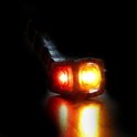 Zwarte LED-markeringslamp met rood en oranje licht, gepresenteerd tegen een donkere achtergrond.