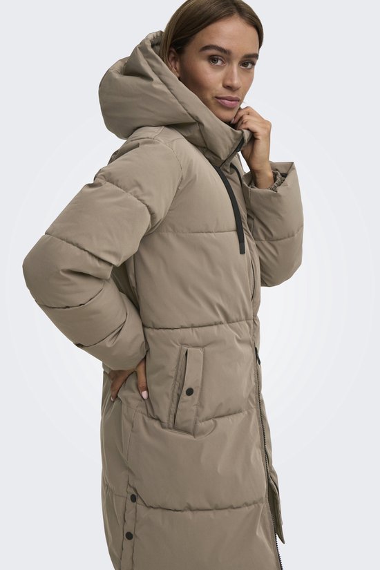Model in lang, beige gewatteerd jack met capuchon, met zwarte trekkoorden en drukknoopzak.