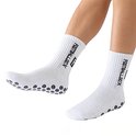 Benen van een persoon met witte voetbalsokken met zwarte "FS FOOTBALL SOCKS" tekst en anti-slip nopjes.