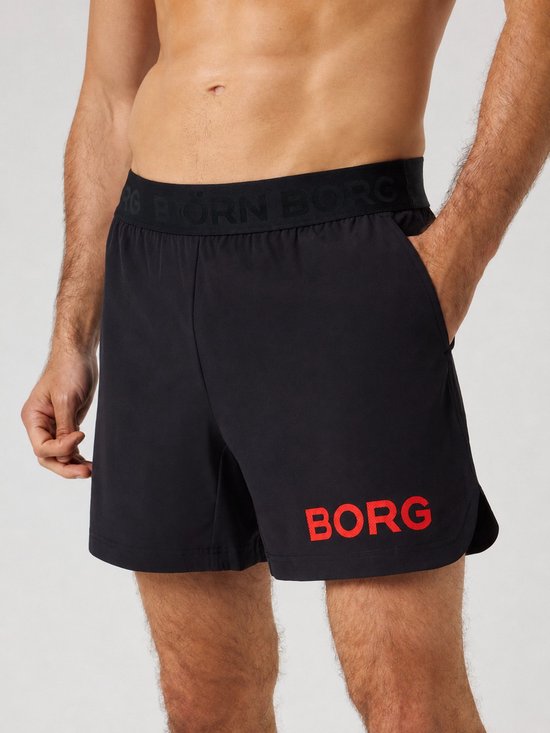 Zwarte korte sportbroek met BORG-logo op de tailleband, rode 'BORG'-opdruk op de pijp, gedragen door een man.