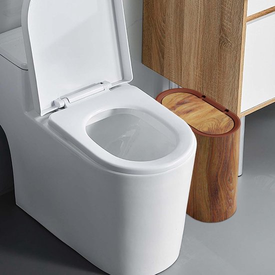 Ovale afvalbak met houtlook naast een toilet in een badkamer.