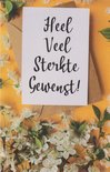 Wenskaart met de tekst 'Heel Veel Sterkte Gewenst!' op een witte kaart, omringd door bloesems en een bruine envelop.