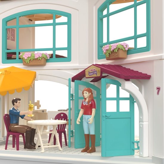 Meisje en jongen bij een tafel met parasol voor de ingang van de 'Lakeside Horse Club'.