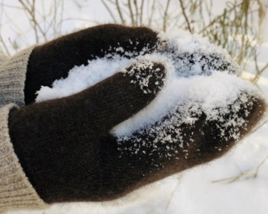 Donkerbruine wollen wanten die sneeuw vasthouden in de handen.