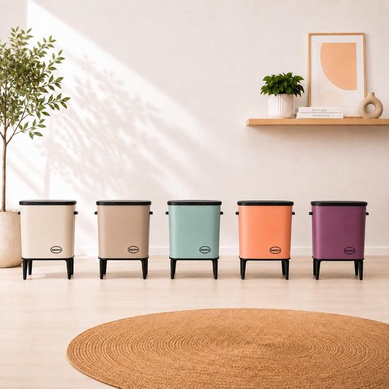 Vijf Barero prullenbakken in verschillende kleuren: crème, taupe, mintgroen, oranje en paars, op zwarte poten.
