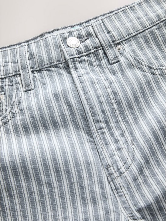 Sluiting van een lichtgrijze denim jeans met witte verticale strepen, knoop en ritssluiting.