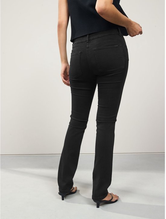 Achteraanzicht van een model in een zwarte slim-fit jeans met achterzakken en een metalen 'NEXT' label.