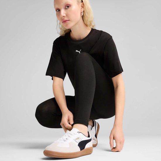 Een vrouw in zwarte PUMA legging en sneakers, hurkend.