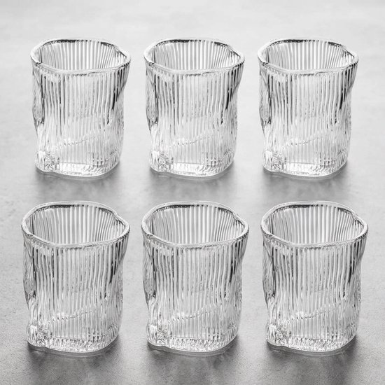 Six verres à boire en verre transparent avec une surface côtelée et torsadée, sur fond gris.